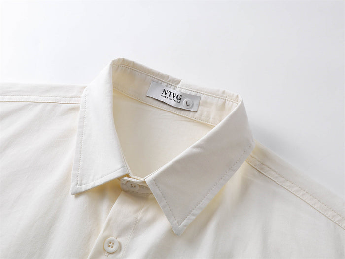 Close-up of cream shirt collar, button placket, and stitched label