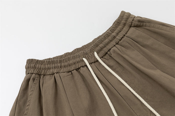 Close-up of taupe brown pants showing the gathered elastic waistband and white drawstrings