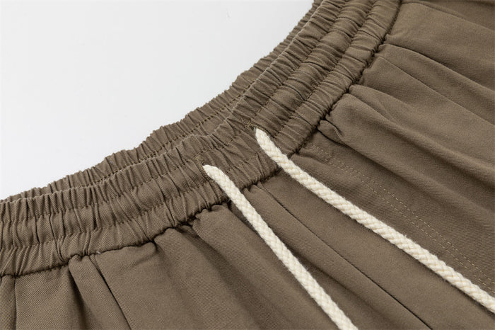 Detailed close-up of the elastic waistband and white drawstrings on taupe brown pants