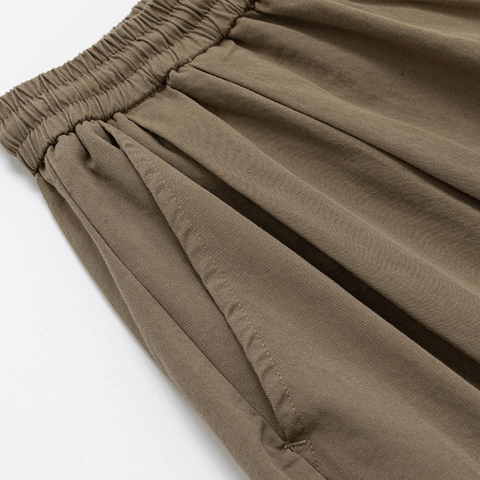 Close-up of taupe brown pants showing the side seam, pocket opening, and gathered waist
