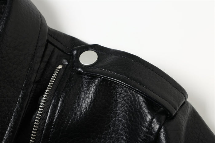 Close-up of black jacket shoulder epaulet with silver snap and zipper detail