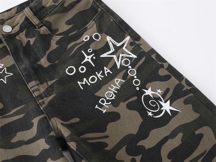 Close-up of white star and letter graphics printed on the camouflage jeans upper leg
