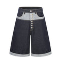Men's dark indigo contrast patchwork wide-leg denim shorts with exposed button fly and rolled cuff hem, front view