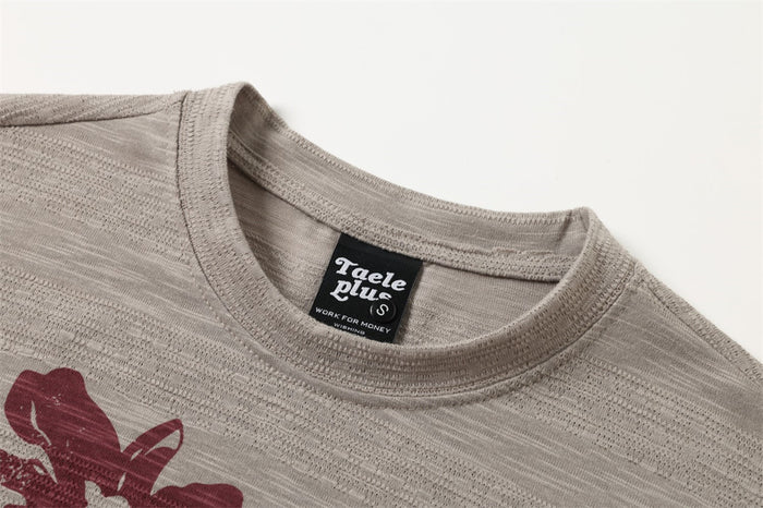 Close-up of the taupe tee's ribbed crew neckline, inner label, and floral print edge