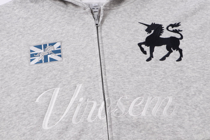 Front chest view of light gray zip hoodie with unicorn patch, black crest, and embroidered logo
