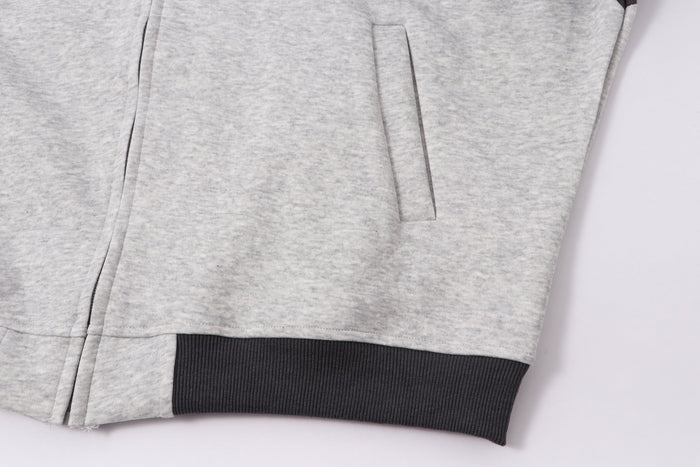 Lower front view of light gray hoodie with pocket, side seam, and ribbed hem