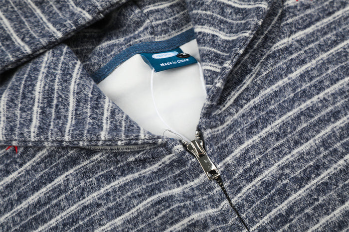 Detailed view of the navy striped hoodie neckline showing the fabric label and metal zipper pull
