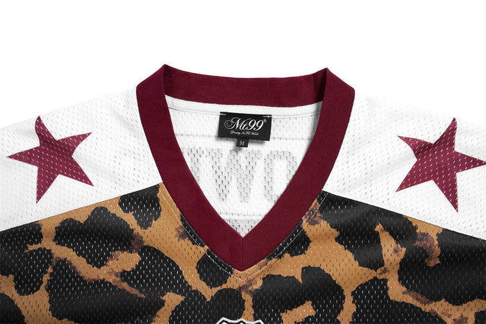 Close-up of the jersey front showing a burgundy V-neck, white shoulders with burgundy stars and leopard print mesh