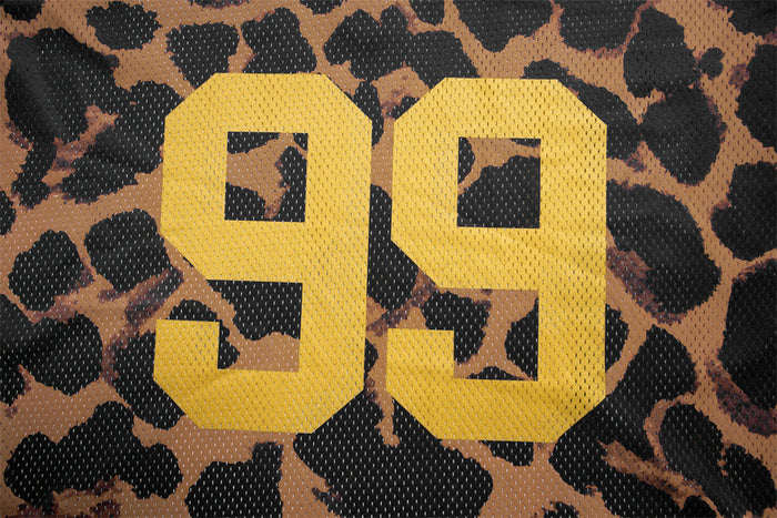 Close-up of the large yellow number 99 printed over the brown and black leopard print jersey fabric
