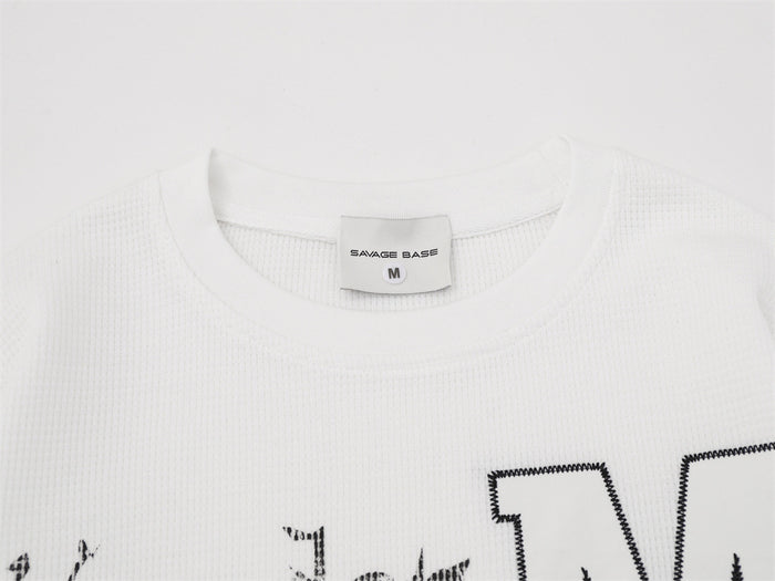 Close-up of the white shirt ribbed crew neckline, woven size label, and waffle knit texture