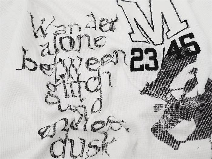 Close-up of white shirt front graphics showing layered text, outlined M, 23/45 numbers, and abstract print