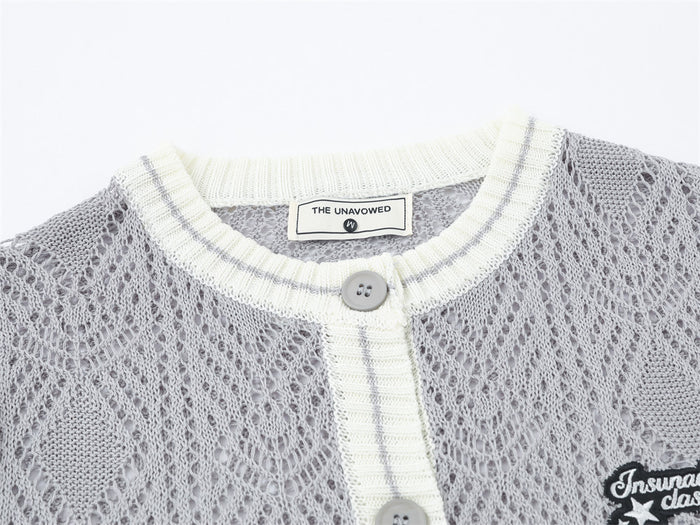Close-up of gray cardigan neckline showing cream striped ribbing, button closure, woven label, and open-knit texture