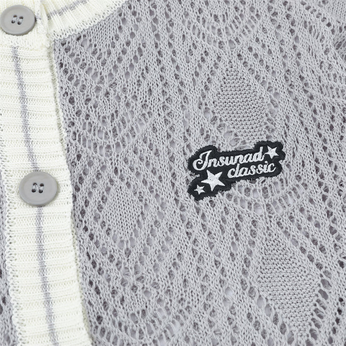 Gray open-knit cardigan chest detail with diamond texture, cream button band, round buttons, and embroidered patch
