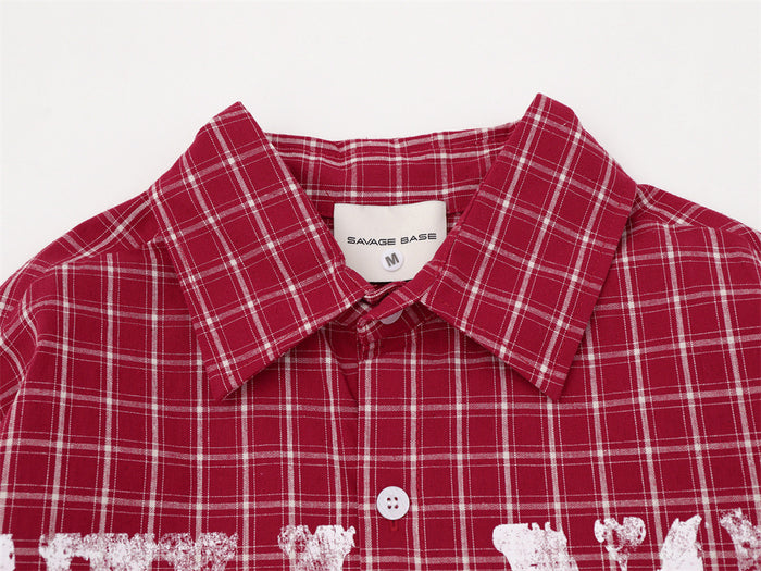 Close-up of the red plaid shirt collar, top buttons, and distressed white chest lettering