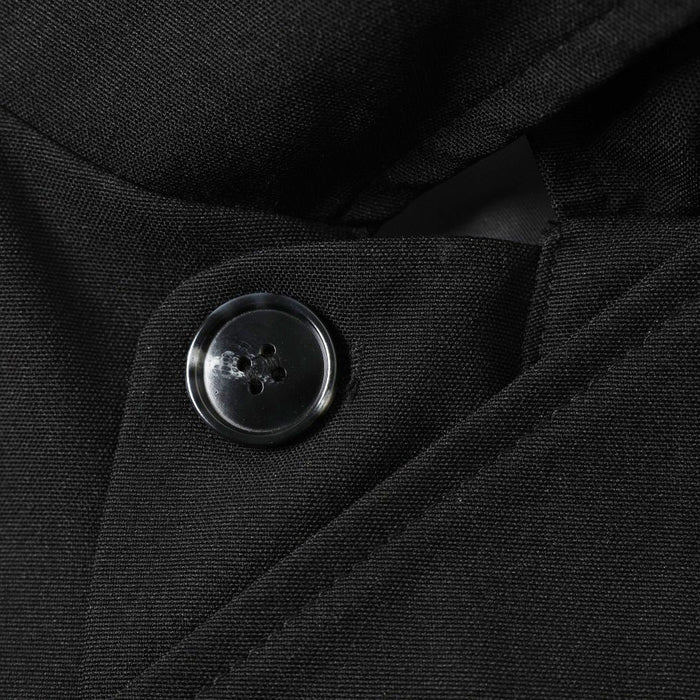 Close-up of black button fastening on the diagonal placket