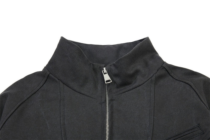 Close-up of the black bomber jacket stand collar and central metal zipper with sculptural shoulder seams