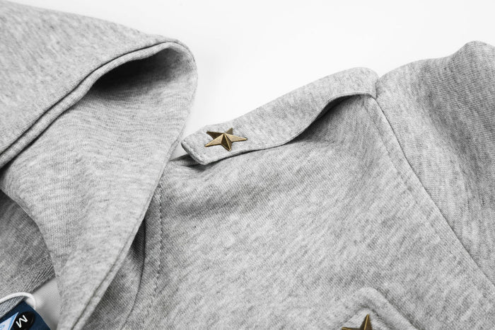 Close-up of the gray hoodie jacket shoulder flap with a metallic star stud and hood edge