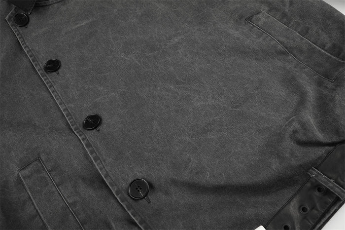 Close-up of charcoal jacket front with asymmetrical buttons and welt pockets