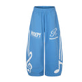 Blue wide-leg sweatpants shown from the front with white treble clef, note, stripe and logo graphics