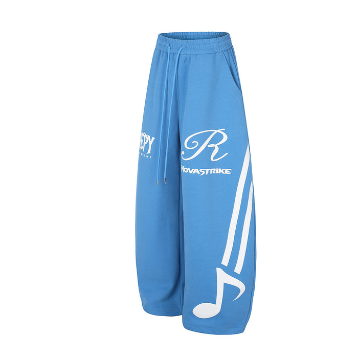 Blue wide-leg sweatpants in an angled front view highlighting the large white note and side stripes