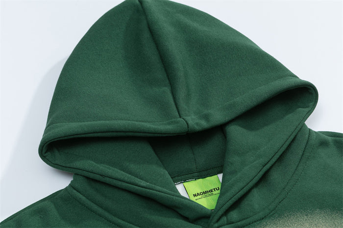 Close-up of the dark green hoodie hood, layered neckline, soft fabric, and sewn-in label
