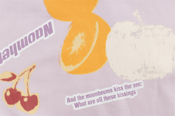 Close-up of the hoodie print showing orange fruit, red cherries, white fruit, and a small text graphic