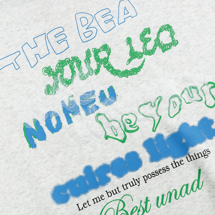 Close-up of the light gray hoodie chest graphic with blue and green layered lettering and textured print