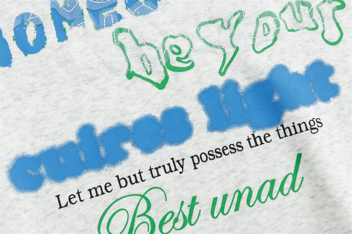 Close-up of the hoodie’s lower graphic showing blue lettering, black text, and green script