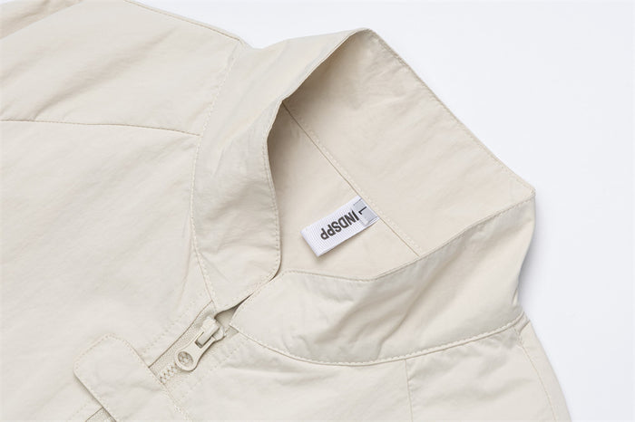 Close-up of the cream jacket’s stand collar, front zipper, stitching, and sewn-in label