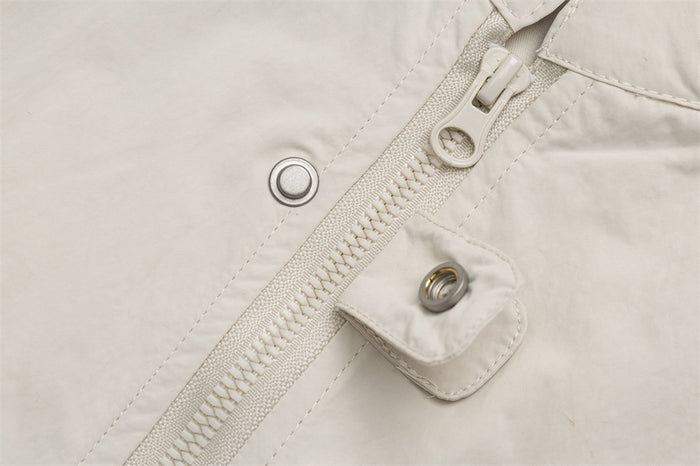 Cream jacket front zipper shown with a snap-button storm flap and metal snap details