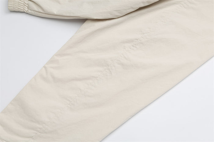 Close-up of the cream jacket sleeve showing its smooth, lightly crinkled woven fabric
