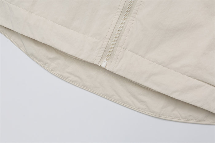 Close-up of the cream jacket’s curved lower hem and adjacent front zipper seam