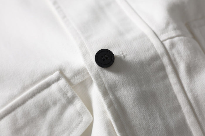 Close-up of white jacket chest pocket flap with black button