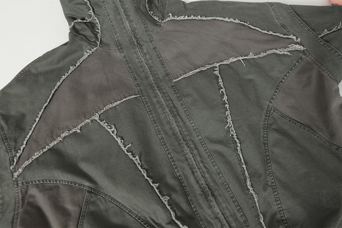 Close-up of charcoal gray patchwork panels and zipper with prominent frayed seam edges