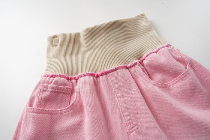 Close-up of the pink washed jeans waistband with beige ribbed knit and frayed top seam