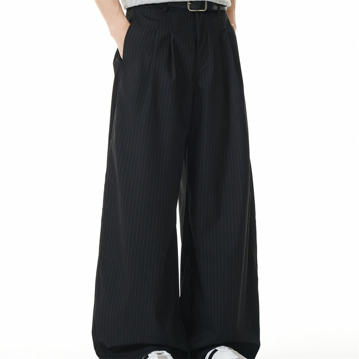 Front view of black pinstripe wide-leg trousers on a model with hands in pockets