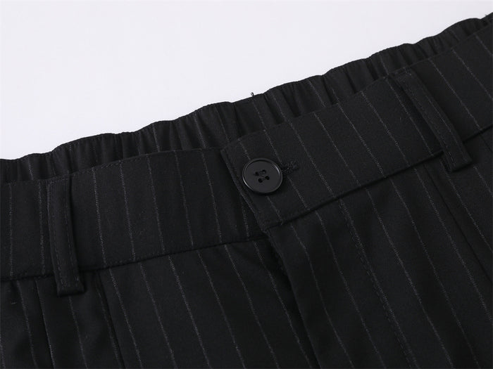 Close-up of black pinstripe waistband with front button and subtle pleats