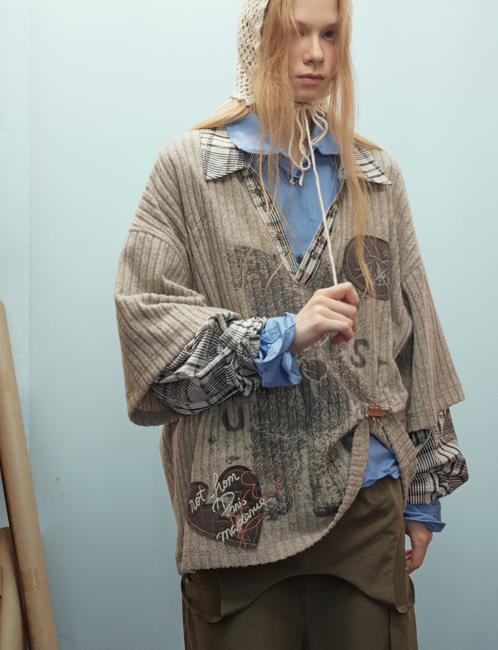 Close front view of beige layered bear graphic sweater with plaid collar and sleeves on model