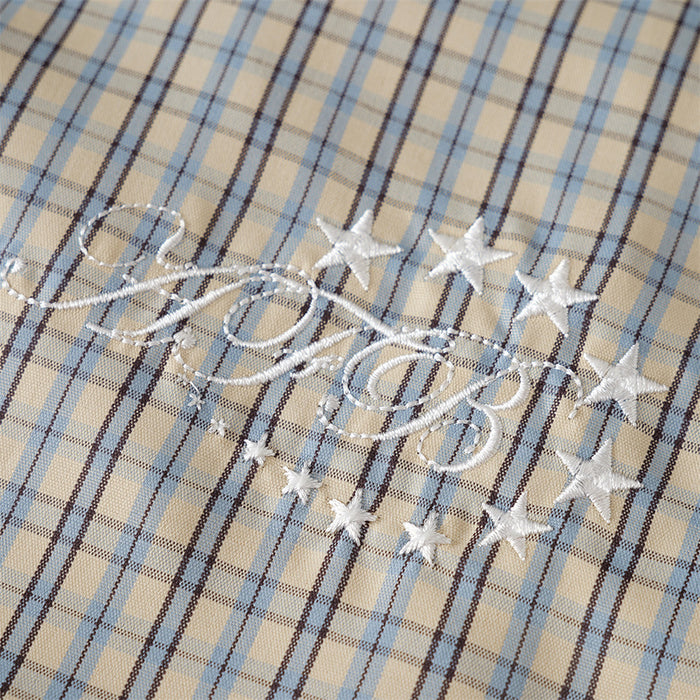 Close-up of embroidered chest graphic on beige-blue plaid shirt