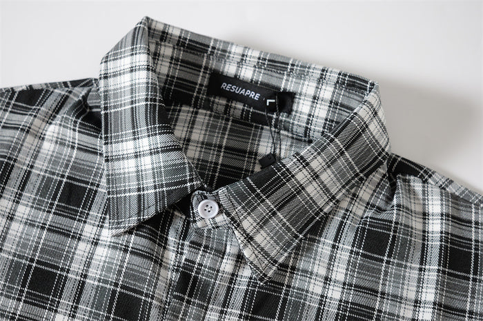 Close-up of black-and-white plaid collar with button placket and woven brand label