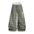 Oversized brown plaid wide-leg parachute pants with white elastic waistband and distressed letter graphics, front and back vi