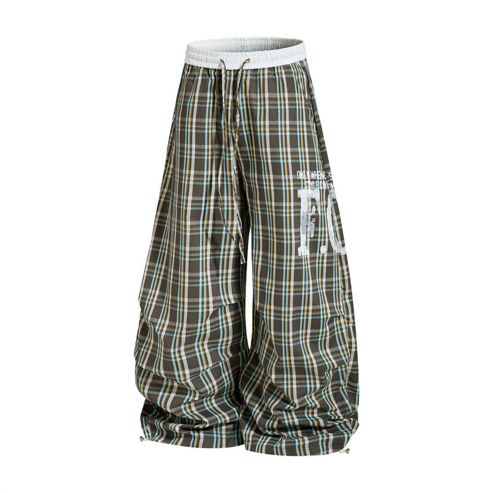 Front view of plaid wide-leg parachute pants with oversized drape and printed side graphic