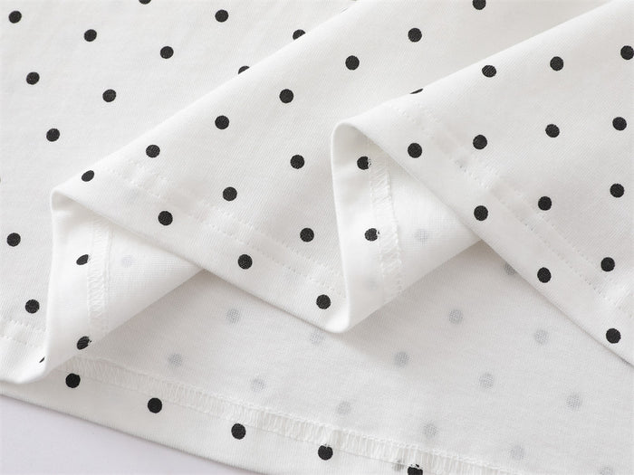 Close-up of white T-shirt hem and sleeve edge with black polka dot print