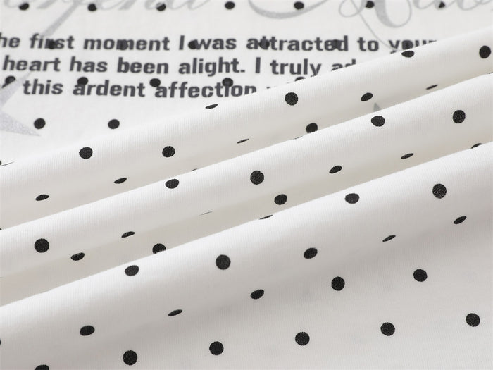 Close-up of folded white polka dot fabric with front text visible in the background