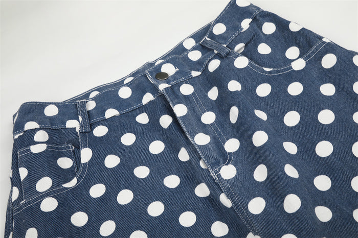 Close-up of blue polka dot pants showing the waistband, belt loop, front pocket, button, and zipper