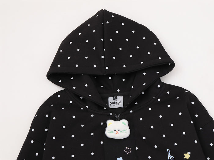 Close view of black polka dot hoodie front with plush cat patch and star details