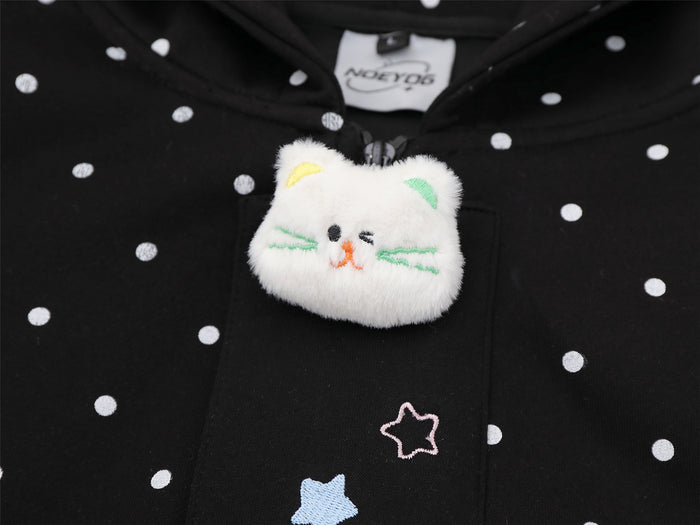 Close-up of a raised white cat patch with colored facial details on a black polka dot hoodie