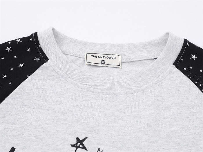 Close-up of the light gray crew neckline and black star-print raglan shoulder panels