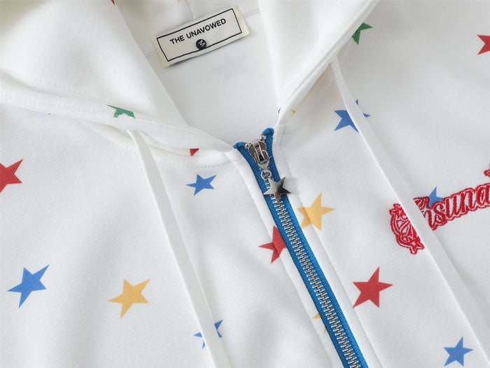 Close-up of the white star-print hoodie neckline with label, drawstrings, blue zipper, and chest embroidery