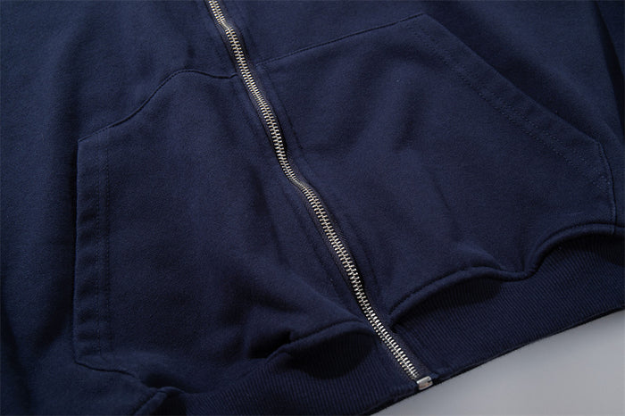 Close-up of the silver front zipper, kangaroo pocket seam, navy body, and ribbed hem